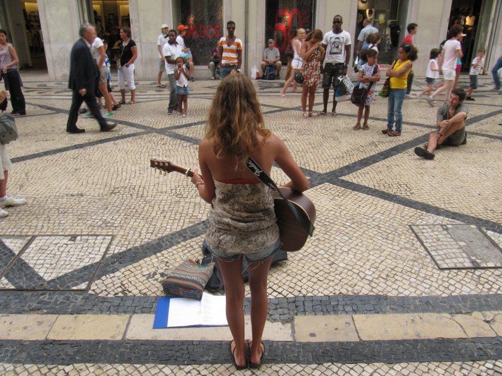 Una joven toca la guitarra en una calle de Lisboa.