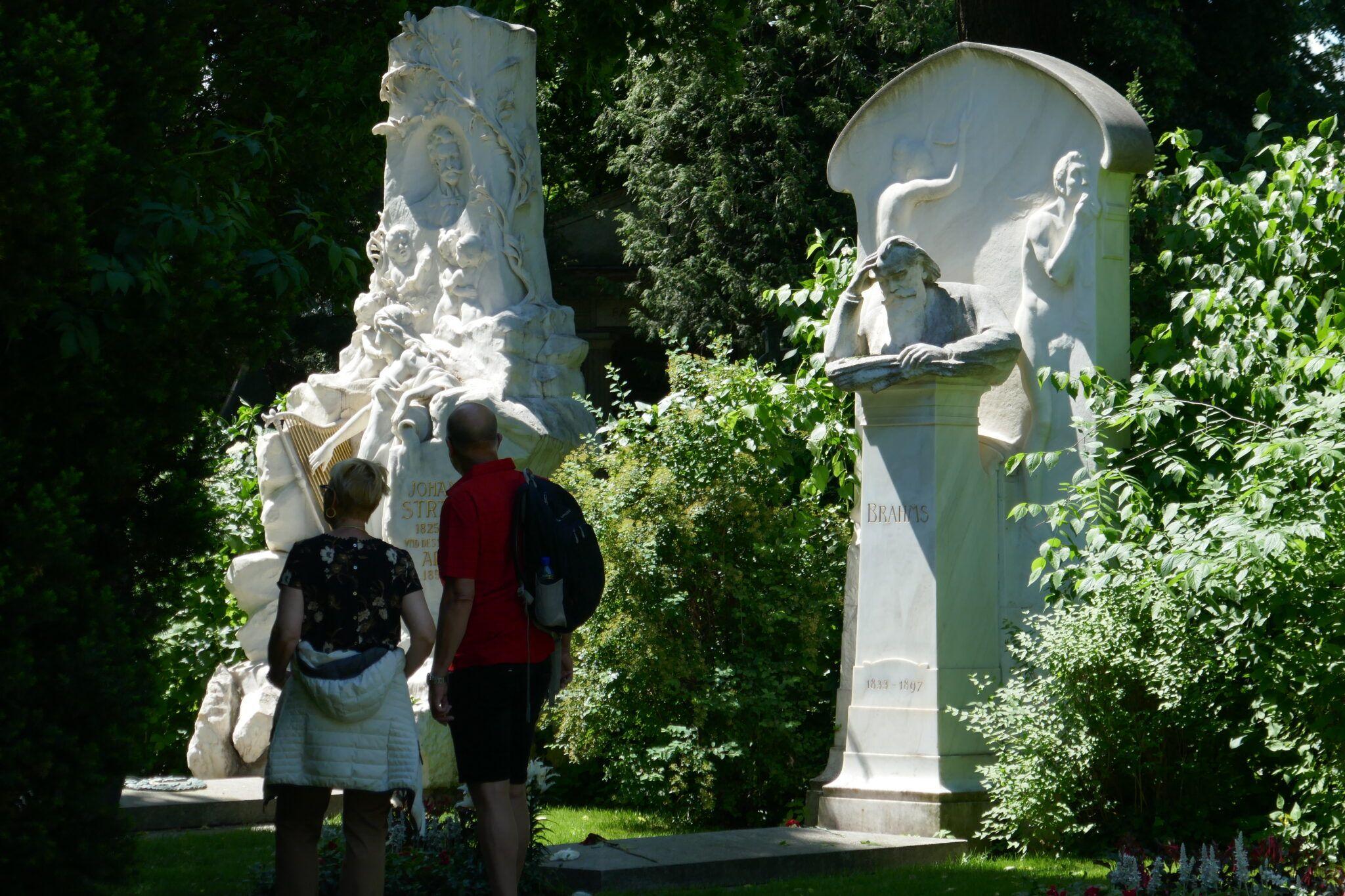 Dos visitantes del cementerio central de Viena ante las tumbas de Brahms y Johann Strauss hijo.