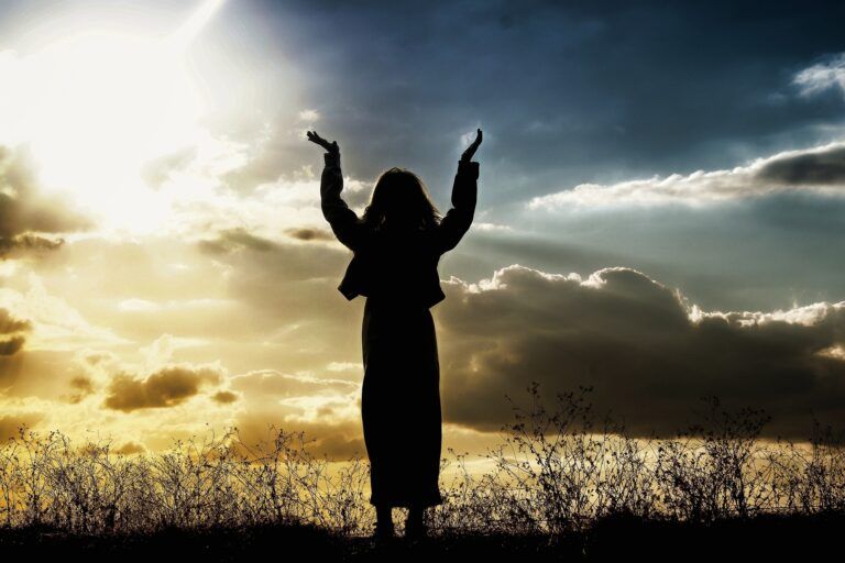 Una mujer alzando los brazos al cielo.