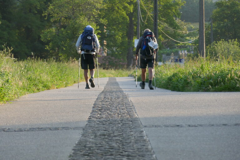 Dos peregrinos caminan por una larga recta en la última etapa del Camino Portugués.