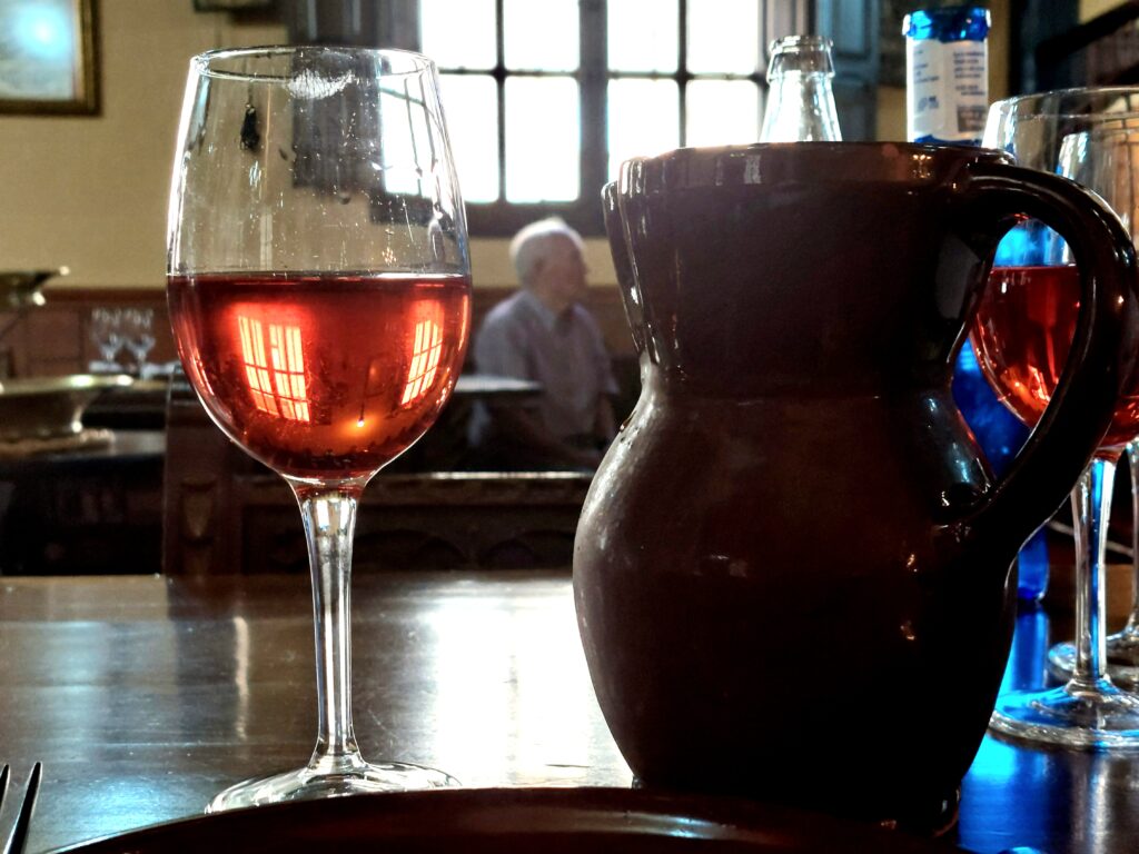 Una jarra de vino para acompañar el lechazo. Al fondo, uno de los hermanos propietarios del Mesón Los Templarios, conversando con los clientes.